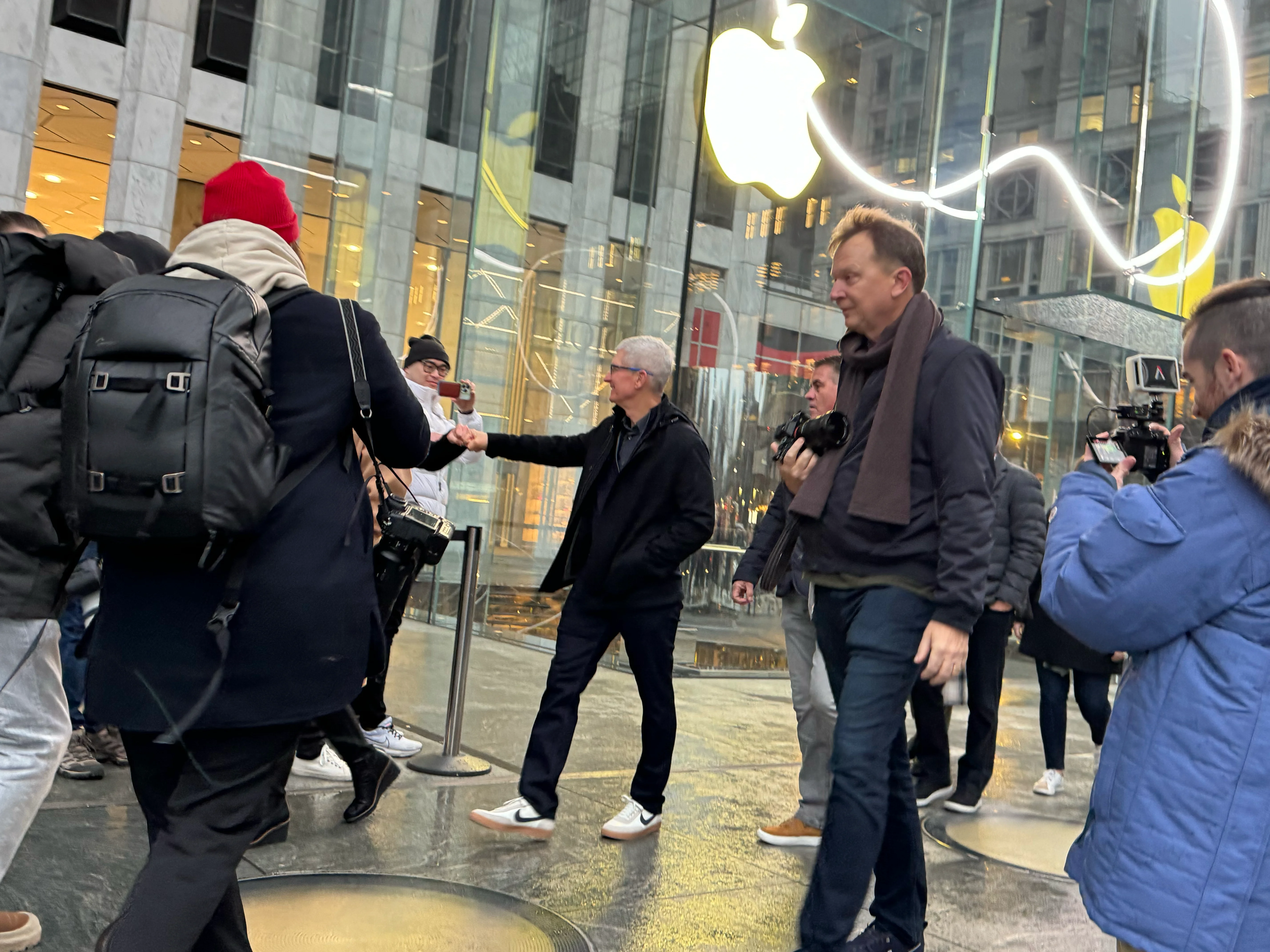 Tim Cook fist bumping people in the queue, Greg Joswiak behind